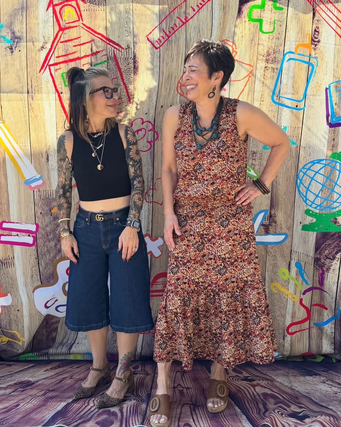 Two women laughing at the Back 2 School Stroll colorful backdrop