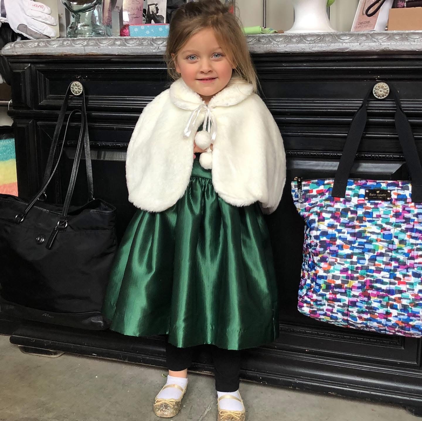 Little girl in green dress with white fur cape at Twice Blessed boutique