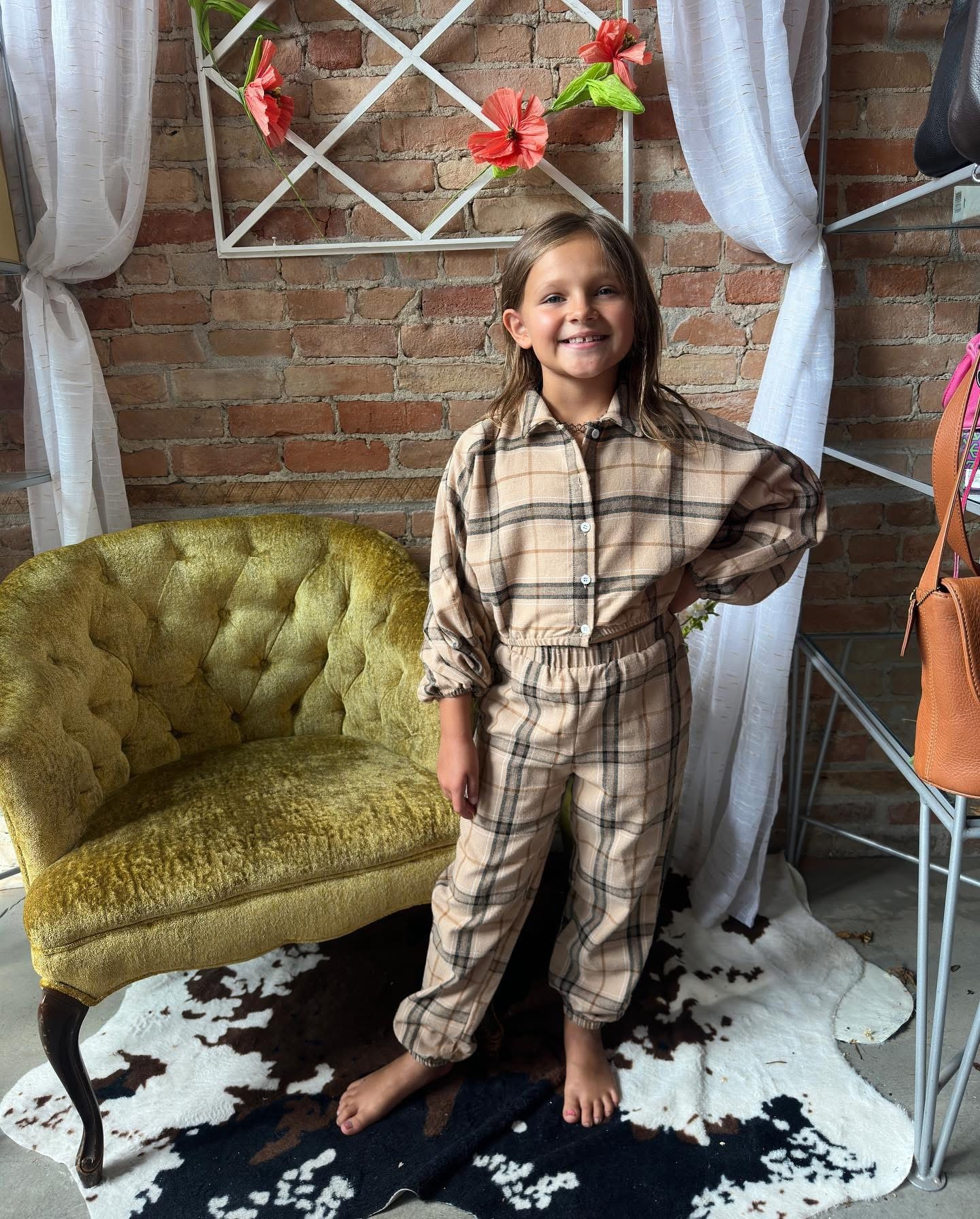 Little girl in tan plaid jumpsuit posing at Twice Blessed boutique