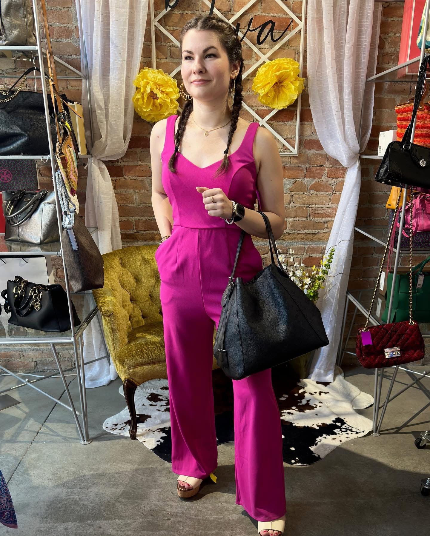 Woman in magenta wide-leg jumpsuit with black bag at Twice Blessed boutique