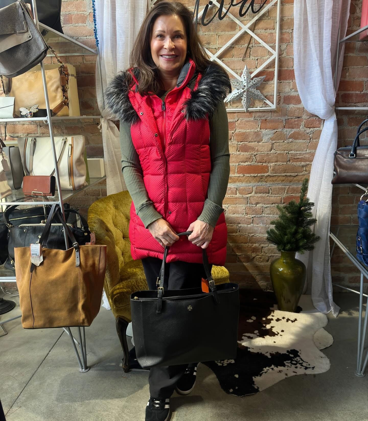 Woman in red fur-trim puffer vest holding a Tory Burch tote at Twice Blessed boutique