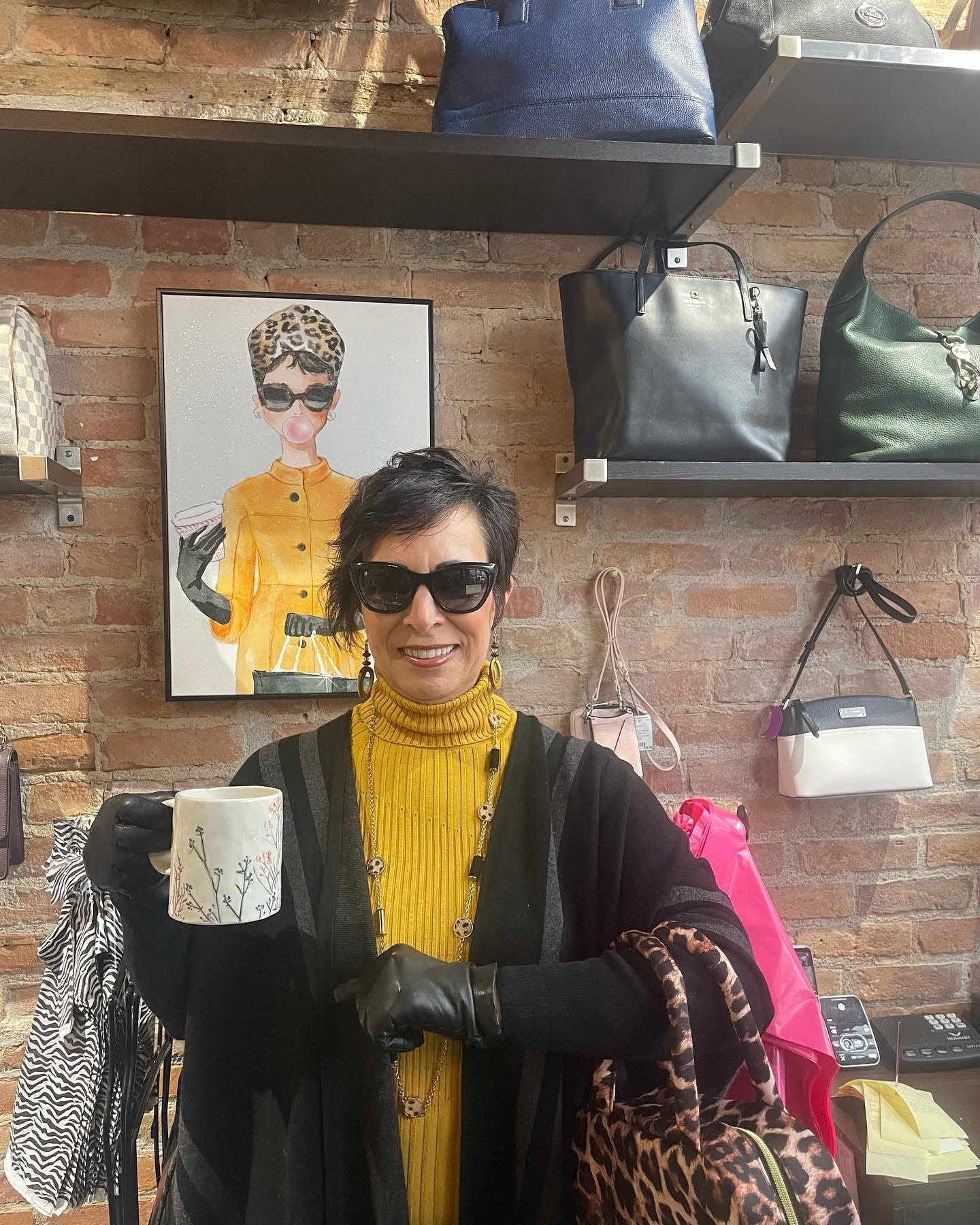 Woman in yellow turtleneck and black cardigan holding a mug at Twice Blessed boutique