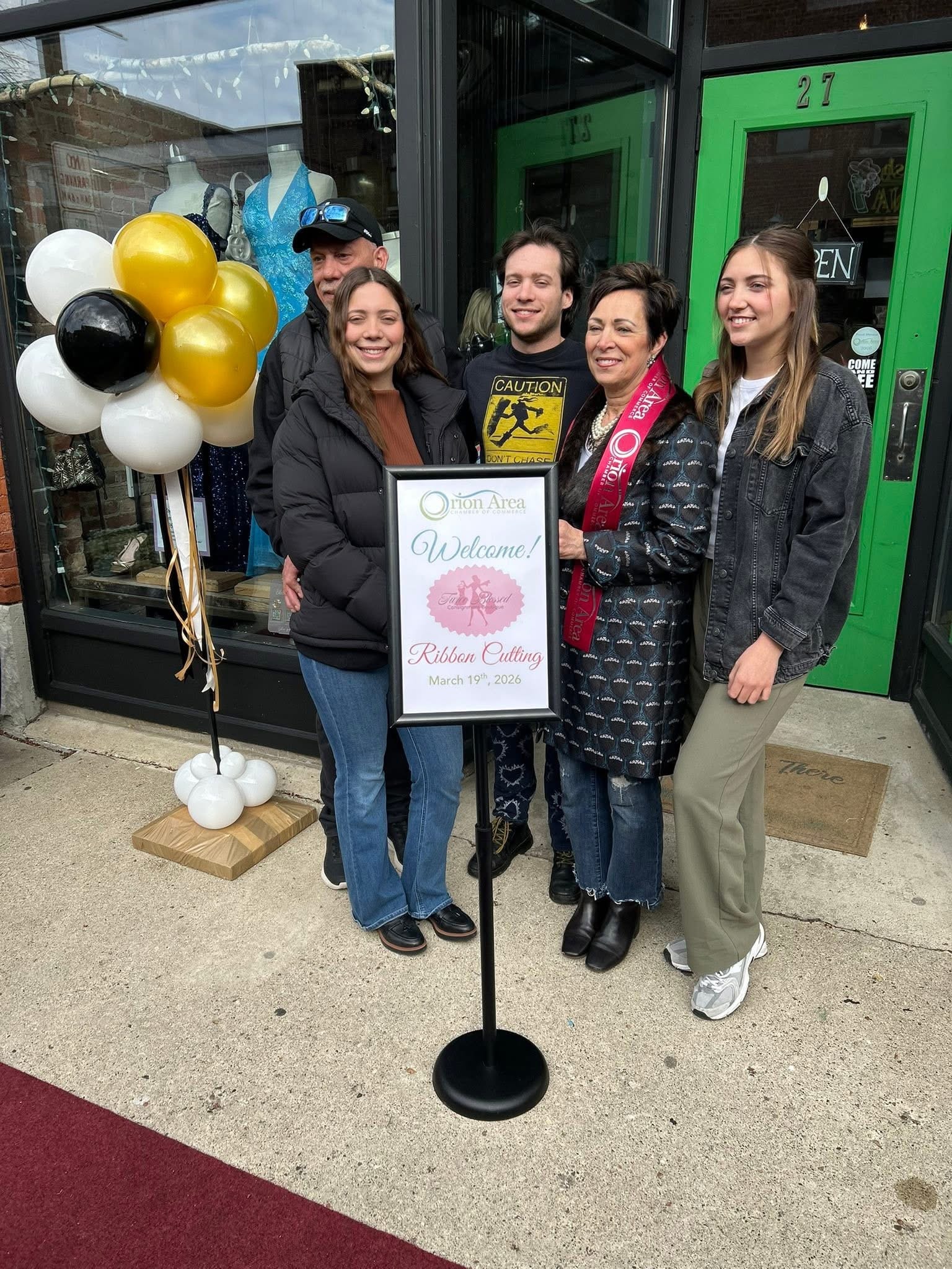 Family posing with the Twice Blessed Ribbon Cutting welcome sign on March 19, 2026