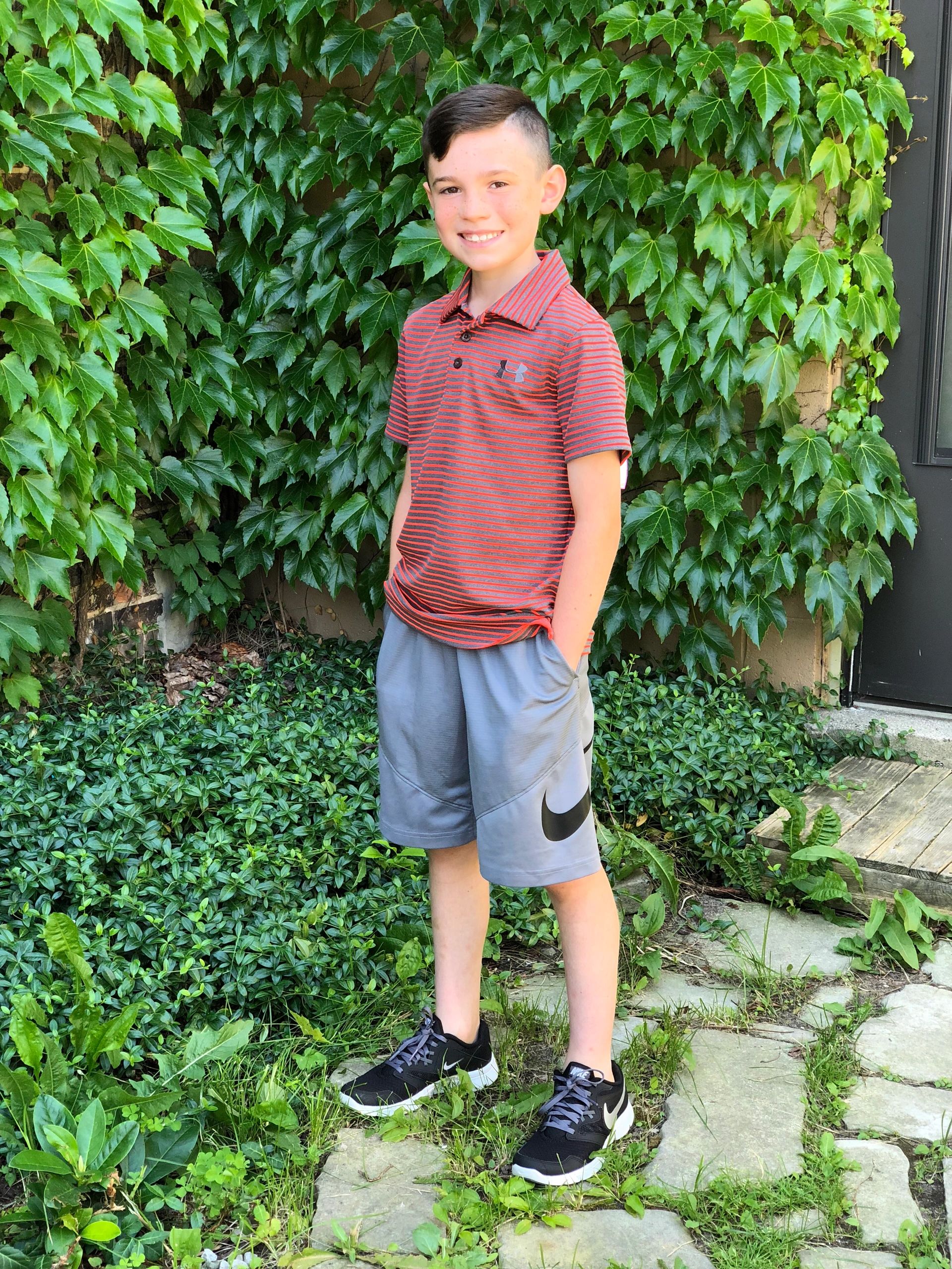 Boy in red striped polo against ivy wall