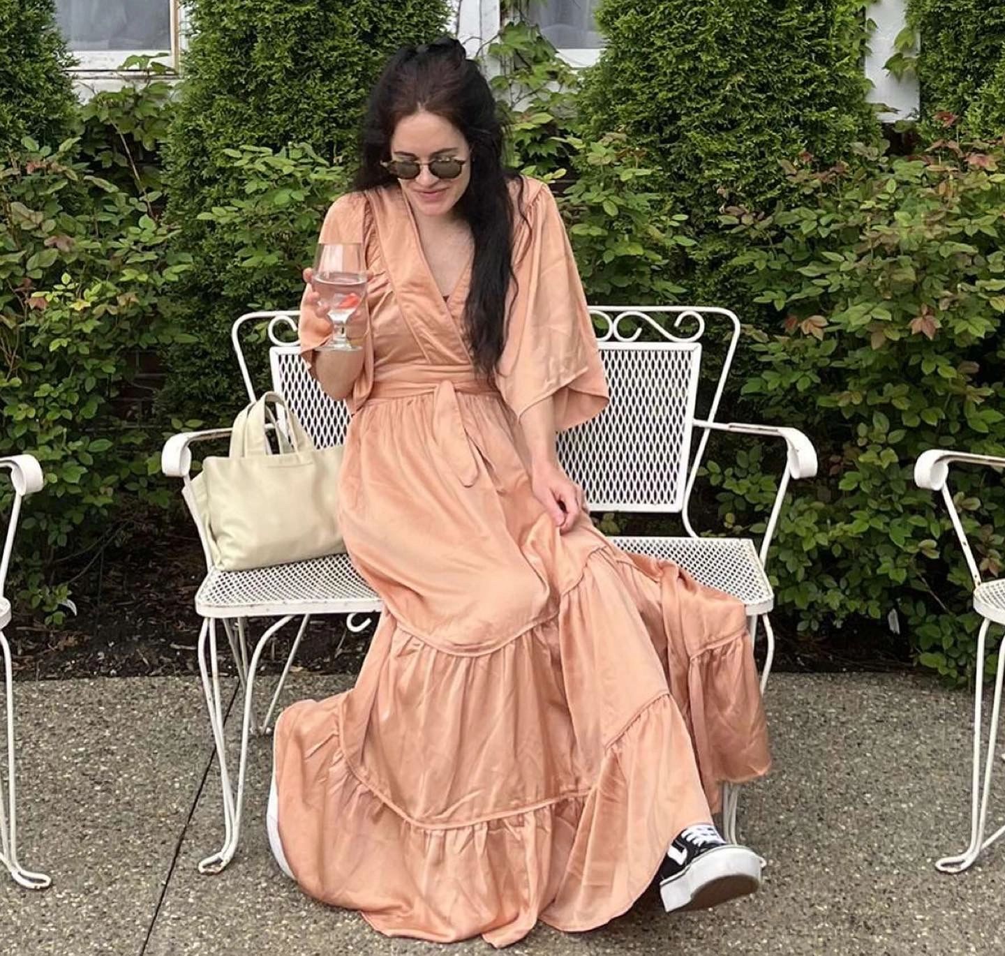 Woman in peach wrap dress with tote bag