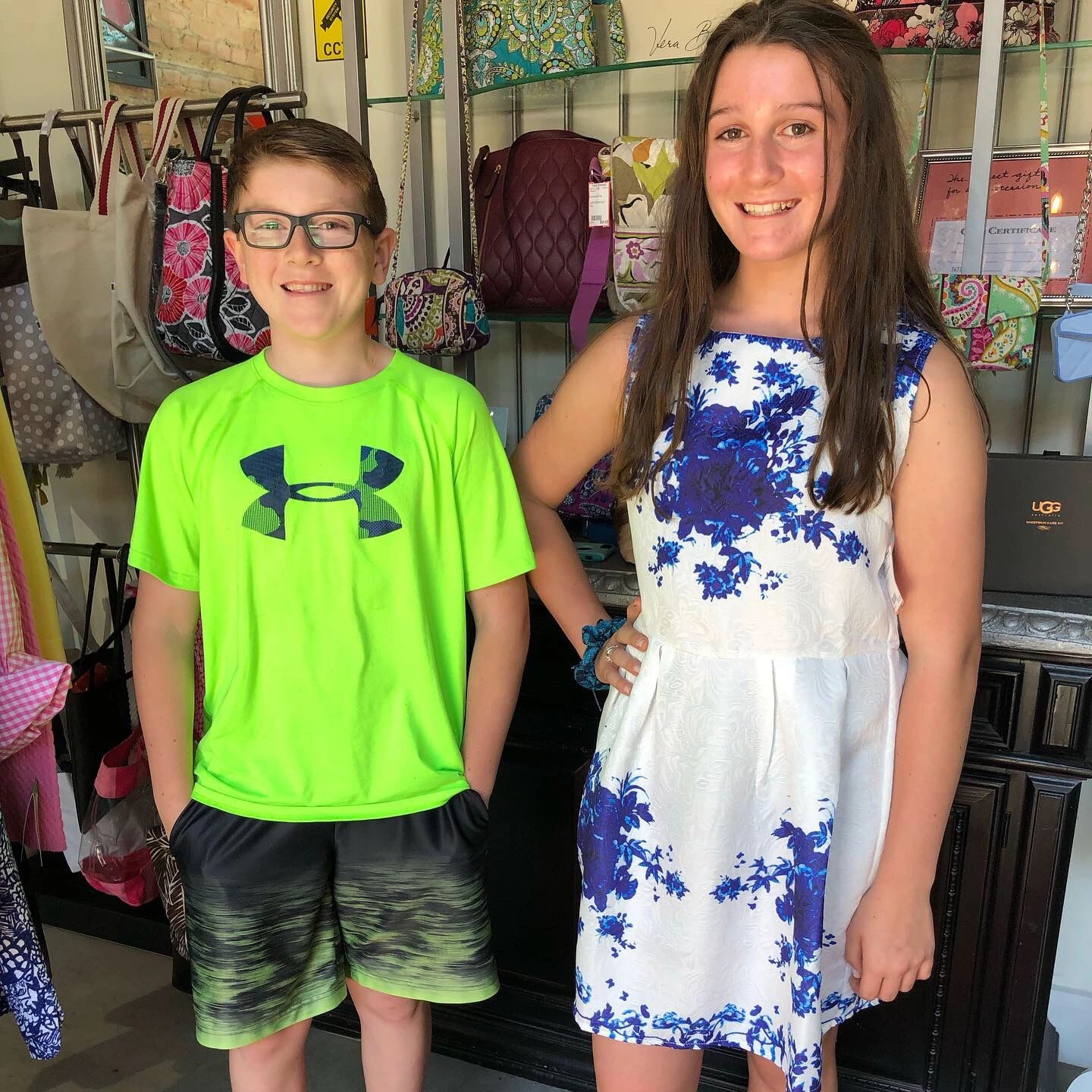 Two kids posing at bags and accessories display