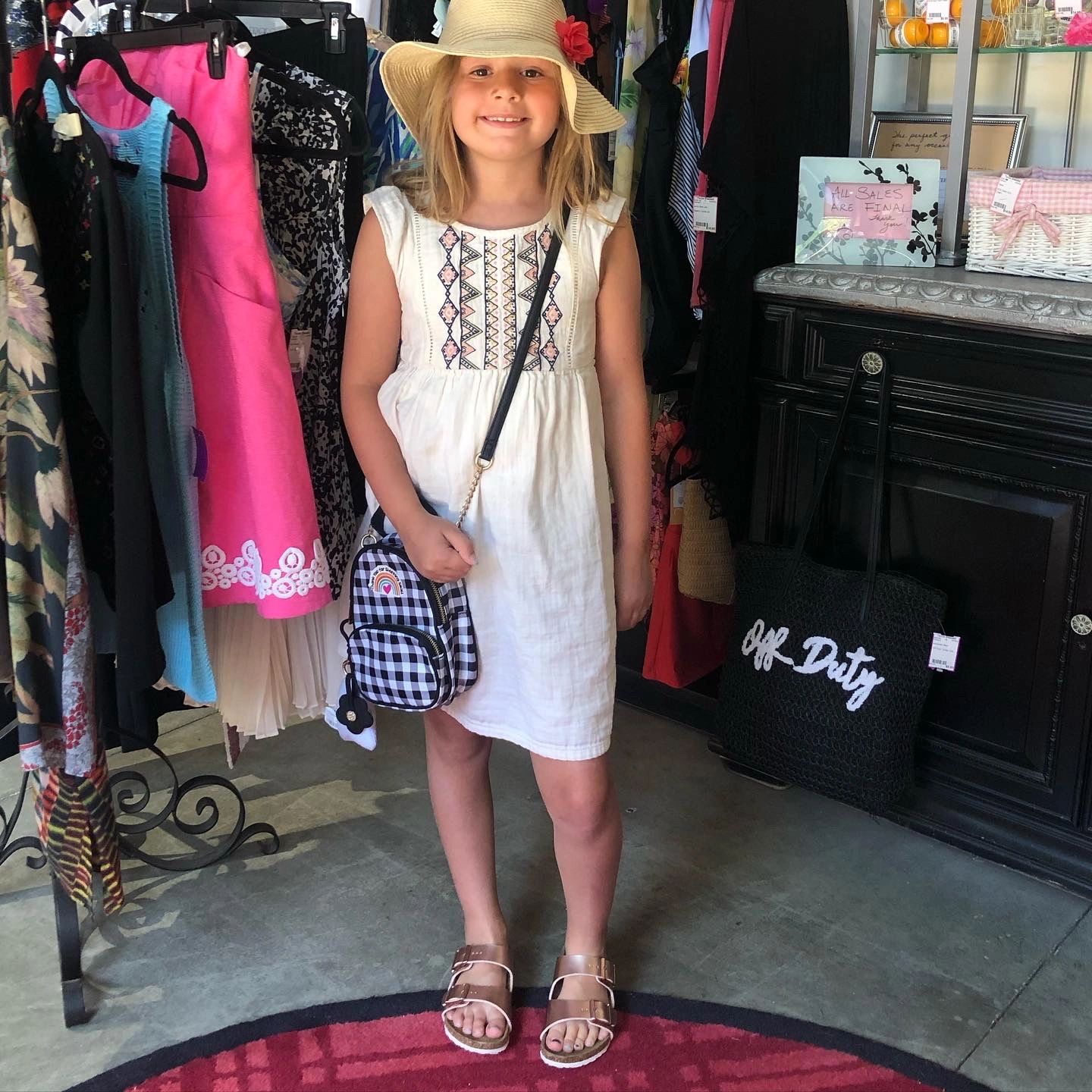 Girl in white embroidered dress and hat at boutique